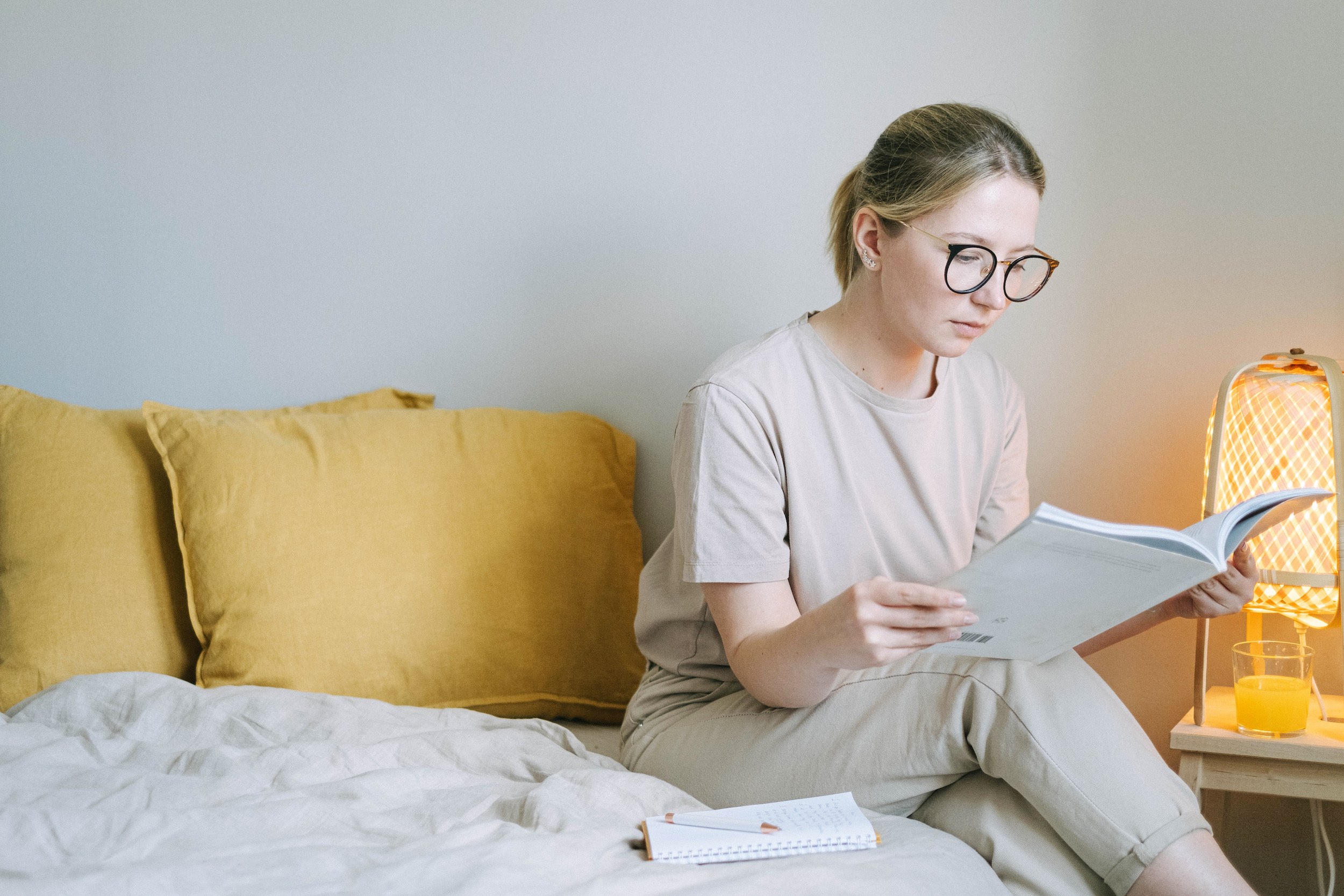 Woman sitting at bedside is focused reading a book