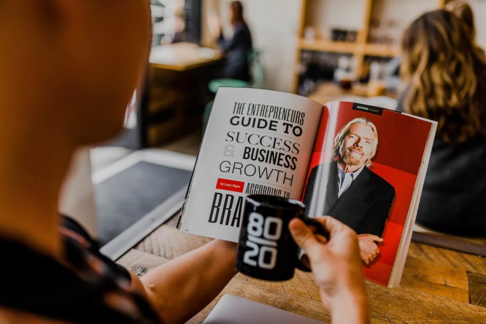 Man drinking coffee stares at a book with a photo of Virgin's founder Richard Branson