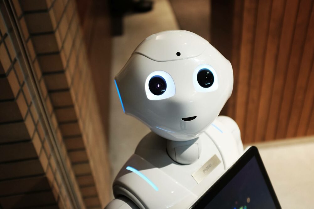 tiny white robot with smily face looks directly at camera