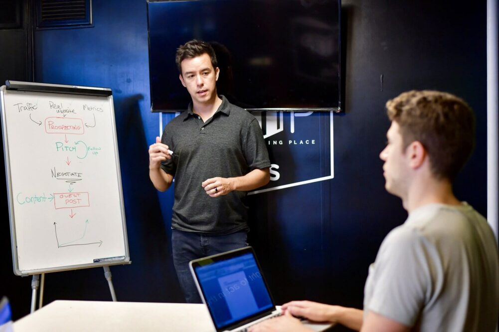 Two young men discuss a flowchart that is presented on a flipboard